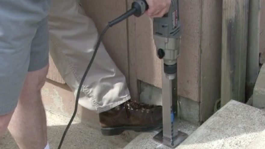 Drill the first concrete anchor hole through the railing base plate